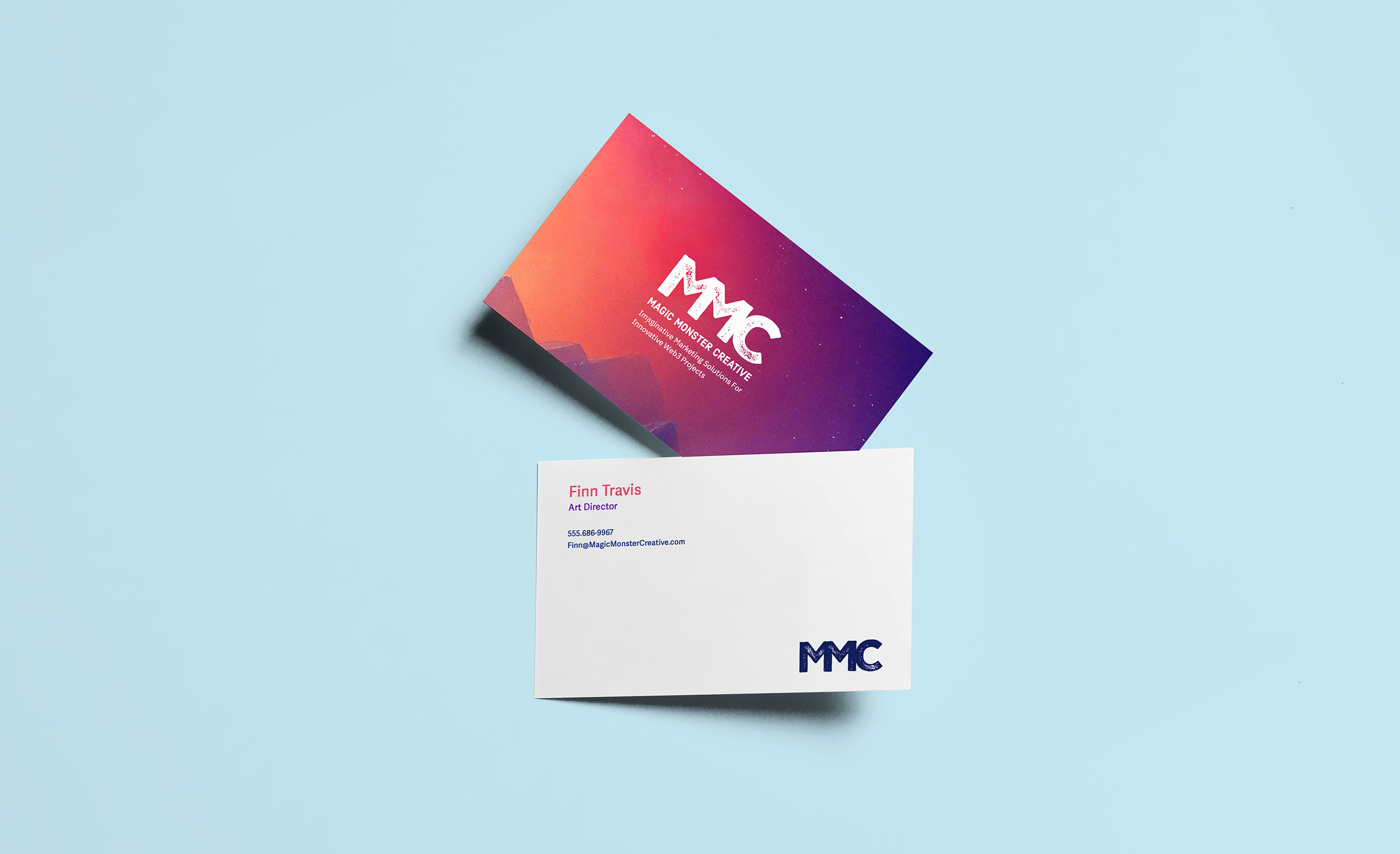 Two business cards on a pale blue surface: a gradient card with the MMC wordmark, and a white card with contact details.